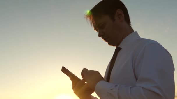 Handen van man rijdt hun vingers over de Tablet PC. man controleert e-mail. Zakenman werken op tablet bij zonsondergang in park. Landbouwingenieur werkt met de tablet in het veld. boer op plantage met — Stockvideo