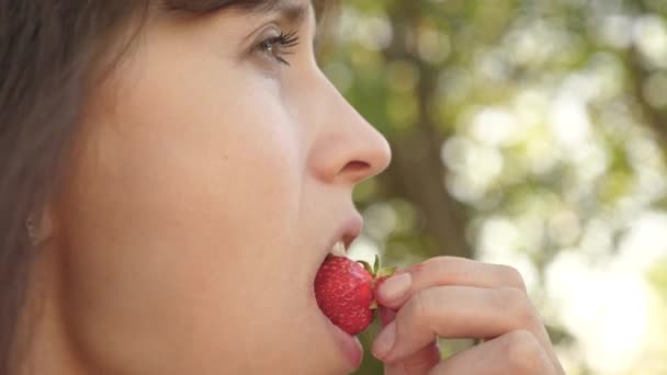 Hermosa chica comiendo arruga de fresa agria y sonriendo. Primer plano. Dieta de vitaminas y bayas para las mujeres. chica feliz comiendo fresas en verano en el jardín. Delicioso postre de fresa . — Vídeos de Stock