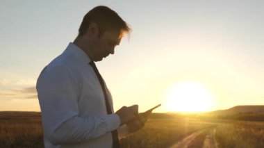 Businessmans parmak dokunmatik ekran tablet, smartphone. Erkek el bir tablet holding ve park e-postalarda günbatımında kontrol. Erkek el smartphone ekranında bir mobil ileti yazmakta olduğunu.