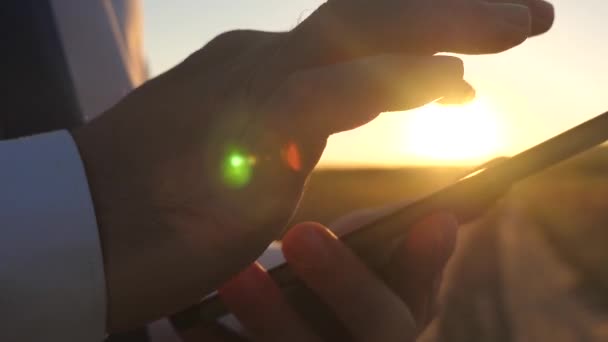 Zakenman werken op een tablet bij zonsondergang. de handen van een man rijdt hun vingers over de tablet. Close-up. man controleert e-mail. — Stockvideo