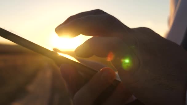 Zakenman werken op een tablet bij zonsondergang. de handen van een man rijdt hun vingers over de tablet. Close-up. man controleert e-mail. — Stockvideo