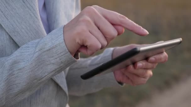 Dedos de niña pantalla táctil de la tableta, smartphone. Primer plano. Las manos femeninas sostienen una tableta y revisan los correos electrónicos en el parque al atardecer. niñas de la mano imprime un mensaje móvil en la pantalla del teléfono inteligente . — Vídeos de Stock