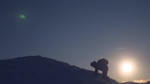 Viajante sobe um pico de montanha. turista fica em uma alta montanha nevada, acena as mãos e se alegra com a vitória ao pôr do sol. Alpenist viaja caminhadas. Mountaineer Viagem às montanhas no inverno . — Vídeo de Stock