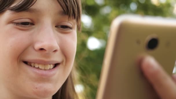 Chica feliz usando el teléfono inteligente hojeando páginas en Internet en un parque en un banco. Primer plano. Joven mujer milenaria en el Arboreto, haciendo gestos en la pantalla del teléfono . — Vídeo de stock