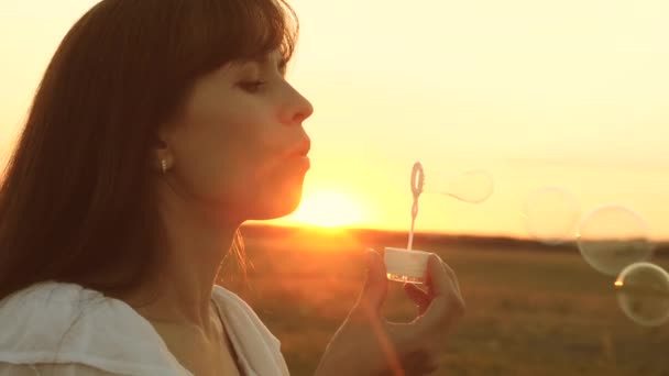 Šťastná dívka v parku na jaře a v létě vyfukoval nádherné mýdlové bubliny. Zpomaleně. mladá dívka odpočívá na slunci. — Stock video