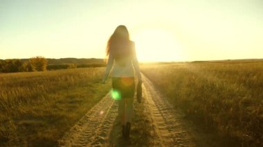 iş kadını onun elinde bir çanta ile köy yolunda yürüyorduk. seksi iş kadını kız kırsal alanda çalışarak. kadın çiftçi kara gün batımında olup olmadığını denetler. tarıma dayalı işletme kavramı.