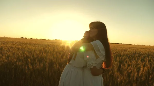 Die erwachsene Tochter im Arm ihrer Mutter auf einem Feld in den Strahlen der Sonne. Mutter streicht ihren Töchtern über die Haare. Mutter umarmt Tochter sanft vor dem Hintergrund eines wunderschönen Sonnenuntergangs. Glückliches Familienkonzept. — Stockfoto