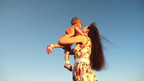 Mamma kastar sin dotter upp till Blu Sky. Slow motion filmning. Mamma leker med små barn i armarna mot himlen. lycklig familj spelar på kvällen mot himlen. mamma kastar upp baby, baby leenden — Stockfoto