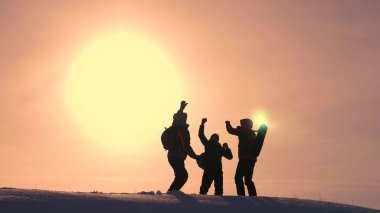 Turistler karlı tepenin üstüne gelir ve sarı bir günbatımı zemin karşı zafer sevinirler. gezginler başarı üstünde bir araya geldi. takım çalışması ve zafer. ekolojik turizm
