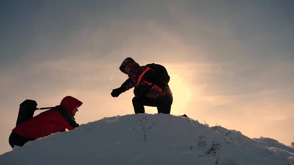 Team work and victory. Tourists extends hand to friend that rises to top of hill. Climbers in winter on snowy mountain work in Kamanda helping to climb a hill. sports tourism concept. — Stock Photo, Image