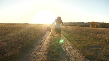 iş kadını onun elinde bir çanta ile köy yolunda yürüyorduk. seksi iş kadını kız kırsal alanda çalışarak. kadın çiftçi kara gün batımında olup olmadığını denetler. tarıma dayalı işletme kavramı.