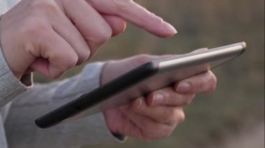 kızlar akıllı telefon ekranında bir mobil mesaj yazdırır. tablet kız dokunmatik ekran parmakları, akıllı telefon. Close. Kadın elleri bir tablet tutuyor ve gün batımında parkta e-postaları kontrol ediyor.