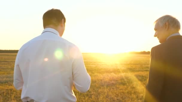 Empresario y granjero negocian al atardecer en el campo. hombres de trabajo en equipo en un proyecto de negocios. Reunión de empresarios en el parque . — Vídeos de Stock