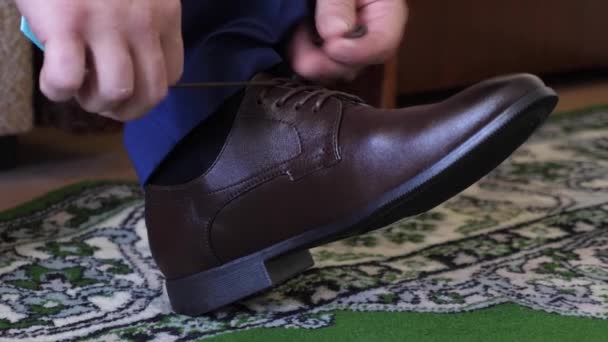 Man knyta skosnören på bruna skor, en man i en vit skjorta och mörka byxor. Affärsman klär på morgonen för att arbeta. — Stockvideo