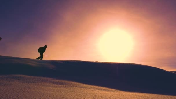 Alpinista de trabalho em equipe no turismo de inverno. os alpinistas passam pela neve no topo do holom.Travelers no inverno vão ao cume de neve, superando dificuldades em raios de um pôr do sol amarelo . — Vídeo de Stock