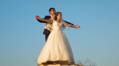 gelin ve damat mavi gökyüzüne karşı dans. Takım çalışması. mutlu aile konsepti. Romantik erkek ve kadın mavi gökyüzüne karşı gezinmek ve gülümseme. Balayı. Romantizm. Bir erkek ve bir kadın arasındaki ilişki.