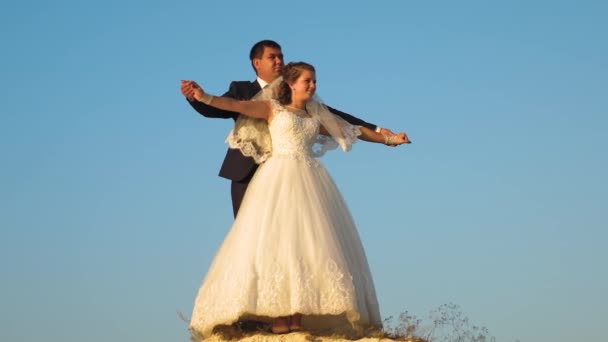 Bride and groom dancing against blue sky. teamwork. happy family concept. Romantic man and woman hover against the blue sky and smile. Honeymoon. Romance. The relationship between a man and a woman. — Stock Video