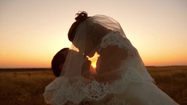 Gelin ve damat gün batımında öpüşür ve sarılır. aşık romantik çift gün batımında öpüşme. Mutlu bir aile kavramı. balayı yeni evliler