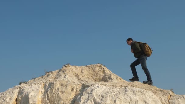 Turistler gökyüzüne karşı tepenin tepesine gider. iş adamlarının takım çalışması. üç dağcı beyaz kaya üzerinde birbiri ardına tırmanıyor. erkek gezginler ekibi zafer ve başarı gider. — Stok video