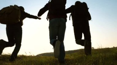 Sırt çantaları ile mutlu turistler koşmak ve ellerini sallamak. iş adamlarının takım çalışması. iş ekibi kazanmak ve başarılı olmak için acele ediyor. Yavaş çekim. neşeli gezginler güneşe tek tek koşmak.