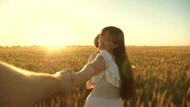 Familia feliz corriendo por el campo tomados de la mano. hermosa niña con su hija camina en el campo con trigo, sosteniendo su amada mano de hombre. feliz madre, niño y papá corren cogidos de la mano, cámara lenta — Vídeos de Stock