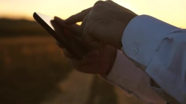 eller adamın parmaklarını tablet üzerinde ilerliyorsunuz. adam e-posta denetler. Tablet üzerinde günbatımında Park'ta çalışma iş adamı. Ziraat Mühendisi tablet alanında çalışır. Çiftçi ile bir çiftlikte