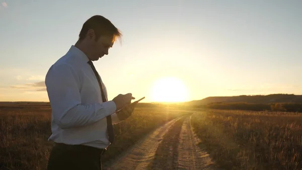 Mãos do homem estão dirigindo seus dedos sobre tablet. homem verifica e-mail. Empresário trabalhando em tablet ao pôr do sol no parque. o agrônomo trabalha com o tablet no campo. agricultor em plantação com — Fotografia de Stock