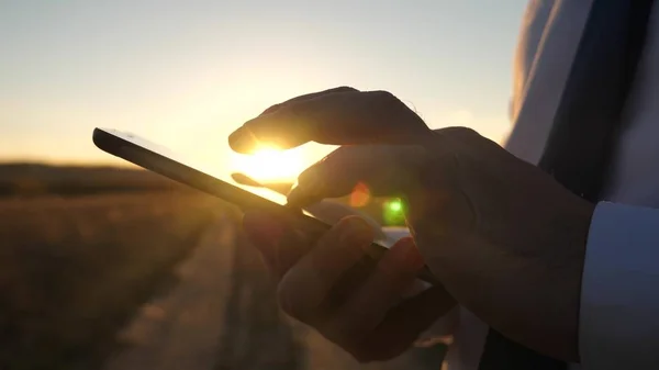 As mãos de um homem estão dirigindo seus dedos sobre o tablet. close-up. homem verifica e-mail. Empresário trabalhando em um tablet ao pôr do sol . — Fotografia de Stock