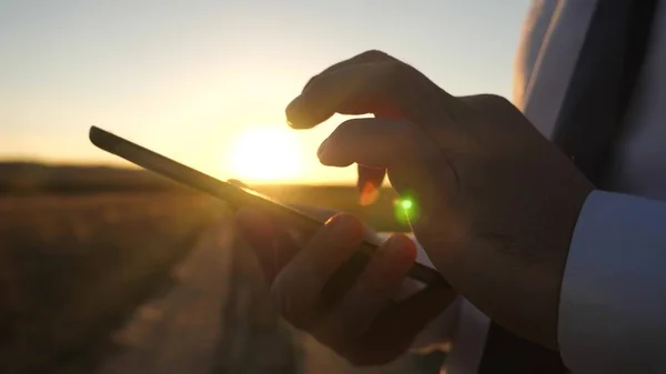 As mãos de um homem estão dirigindo seus dedos sobre o tablet. close-up. homem verifica e-mail. Empresário trabalhando em um tablet ao pôr do sol . — Fotografia de Stock