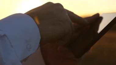 eller adamın parmaklarını tablet üzerinde ilerliyorsunuz. adam e-posta denetler. Tablet üzerinde günbatımında Park'ta çalışma iş adamı. Ziraat Mühendisi tablet alanında çalışır. Çiftçi ile bir çiftlikte