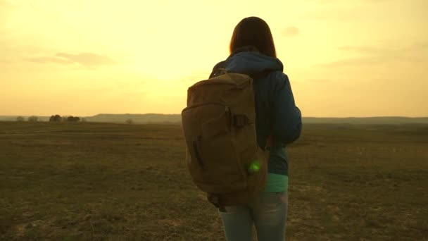 Gökyüzüne ve güneşin parlamasına karşı bir sırt çantası ile seyahat kız. turist genç kadın dağlara bir gün batımına gider. dünya bilgi arzusu. spor turizmi konsepti. — Stok video