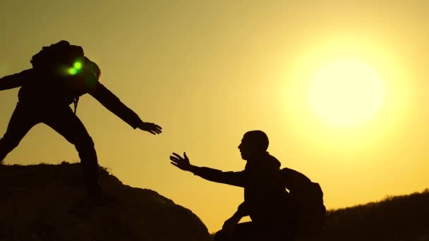 Klimmers silhouetten strekken hun handen naar elkaar, klimmen naar de top van de heuvel. teamwork van zakenmensen. reizigers beklimmen een na de andere op rots. Joint Business. Slow Motion — Stockvideo
