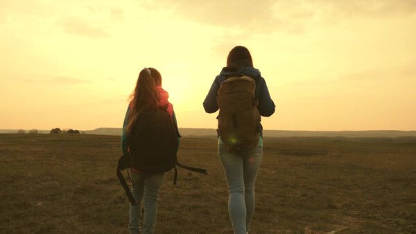 Mom and daughter travel with a backpack against the sky. tourists mother and child go to sunset in the mountains. happy family on vacation travels. sports tourism concept.