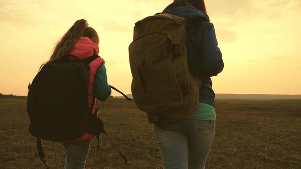 Mom and daughter travel with a backpack against the sky. tourists mother and child go to sunset in the mountains. happy family on vacation travels. sports tourism concept.
