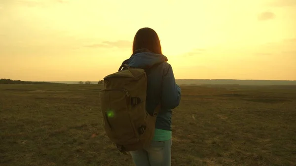 Flicka som reser med en ryggsäck mot himlen och utflytning av solen. turist ung kvinna går på en solnedgång till bergen. önskan om kunskap om världen. sportturism koncept. — Stockfoto
