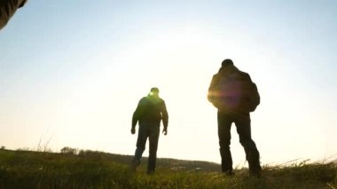 iş adamlarının takım çalışması. İş ekibi kazanmak ve başarılı olmak için acele ediyor. Yavaş çekim. Gezginler teker teker güneşe giderler. turistler sırt çantaları ile seyahat.