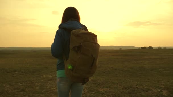 Turista fiatal nő megy a naplemente a hegyekbe. lány utazik egy hátizsákot az ég és a fáklyát a nap. a világ tudásvágy. Sportturizmus koncepció. — Stock videók