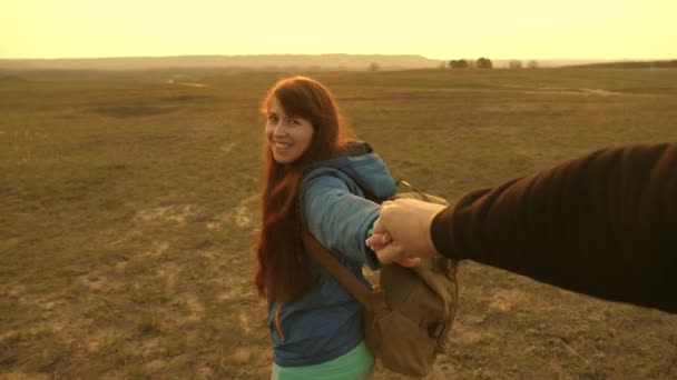 Gelukkige vrouw met rugzak houdt de man bij de hand en leidt hem. Jong stel houdt de handen op reis. kom na mij. werk in een team van toeristen. handen in de liefde zijn reizen bij zonsondergang. — Stockvideo