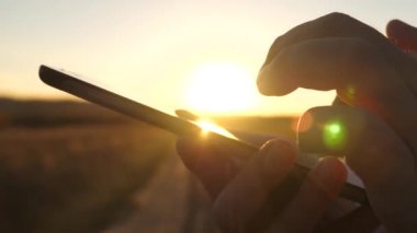 Günbatımında bir tablet üzerinde çalışan iş adamı. Ellerini bir adamın parmaklarını tablet üzerinde ilerliyorsunuz. yakın çekim. e-posta adam denetler.