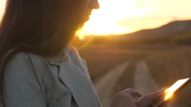 deushkas parmakları tablet boyunca parmaklarını kılavuzu. iş kadını e-posta kontrol eder. Parkta gün batımında tablet üzerinde çalışan iş kadını. Agronomist alanında tablet ile çalışıyor. ile plantasyon üzerinde çiftçi