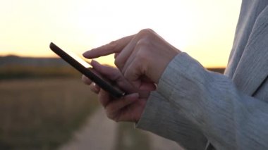 kızın parmak dokunmatik ekran tablet, smartphone. yakın çekim. Eller bir tablet tutarak ve e-postaları parkta günbatımında kontrol. Kızlar el bir mobil ileti smartphone ekranında yazdırır..