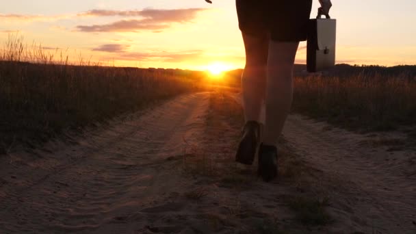 Деловая женщина идет по проселочной дороге с табличкой в руке, солнце miertsaet между женскими ногами. сексуальная деловая девушка, бегающая по сельской местности. сексуальная девушка путешествует по сельской местности — стоковое видео