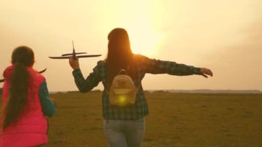 çocuklar oyuncak uçak oynarlar. Mutlu kız kardeşler sahada gün batımında bir oyuncak uçak ile çalıştırın. Mutlu bir aile kavramı. Kızlar uçmayı ve pilot olmayı hayal ler. Yavaş çekim