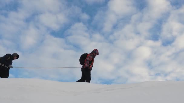 Los escaladores van juntos después de que un amigo atado con una cuerda de seguridad. a lo largo de la cresta de nieve. El equipo de viajeros en invierno va a la cima de la montaña. turismo coordinado de trabajo en equipo en invierno — Vídeos de Stock