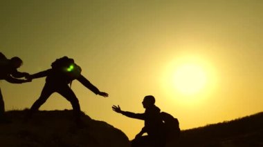 gezginler kayaüzerinde birbiri ardına tırmanıyorlar. ortak iş. Yavaş çekim. iş adamlarının takım çalışması. Dağcısiluetleri ellerini birbirine uzatır, tepenin tepesine tırmanır..