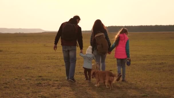 Aile, köpekle birlikte ovaları ve dağları dolaşır. Baba, anne, kızları ve evcil hayvanları, turistler. birbirine sıkı sıkıya bağlı bir ailenin takım çalışması. Doğada bir spor aile tatili kavramı. — Stok video