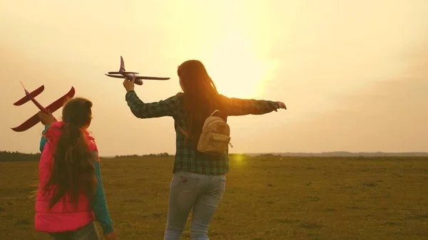 As crianças brincam de avião de brinquedo. Irmãs felizes correm com um avião de brinquedo ao pôr-do-sol no campo. O conceito de uma família feliz. Meninas sonham em voar e se tornar um piloto. Movimento lento — Fotografia de Stock
