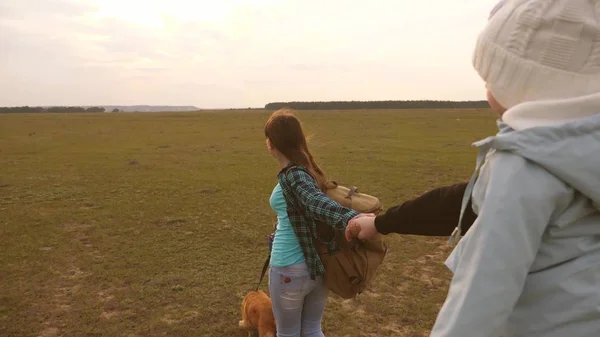 Familie reist met hond op vlakte. kom na mij. Vader met een kleine dochter in zijn armen reist met kinderen en een huisdier. oudste dochter en vader van toeristen gaan hand in hand en glimlach. — Stockfoto