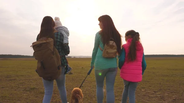 Familia viaja con el perro en la llanura. Trabajo en equipo de una familia muy unida. madre, hijito e hijas y mascotas turistas. El concepto de unas vacaciones en familia deportivas en la naturaleza . — Foto de Stock