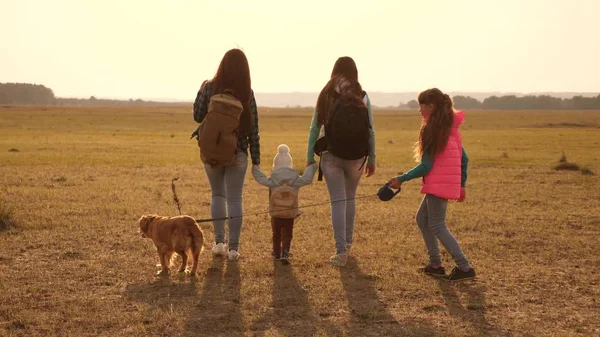 Rodina cestuje se psem přes pláně a hory. matky, dcery a domácí zvířata turistů. Týmová práce rodiny zblízka. Koncept sportovní dovolené v přírodě. — Stock fotografie